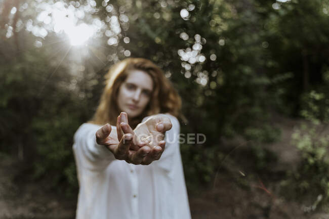 Jeune femme rousse étendant les mains dans la forêt — Photo de stock
