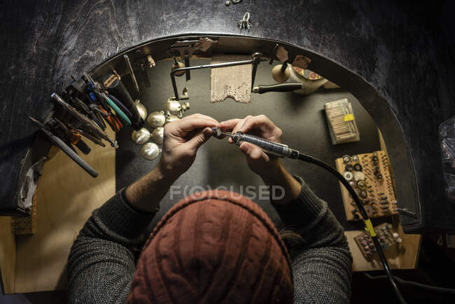 Голдсміт працює над кільцем у своїй майстерні, згори. — стокове фото