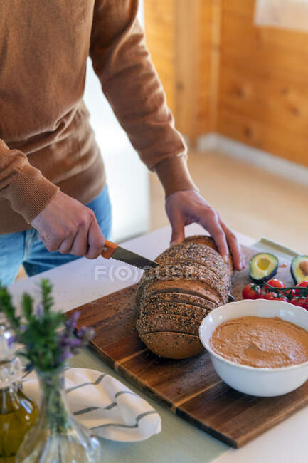Крупный план человека, режущего хлеб в деревянной хижине — стоковое фото