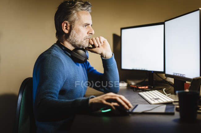 Mature homme assis au bureau à la maison travaillant sur ordinateur — Photo de stock