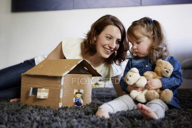Feliz jovem mãe brincando com sua filhinha em casa — Fotografia de Stock