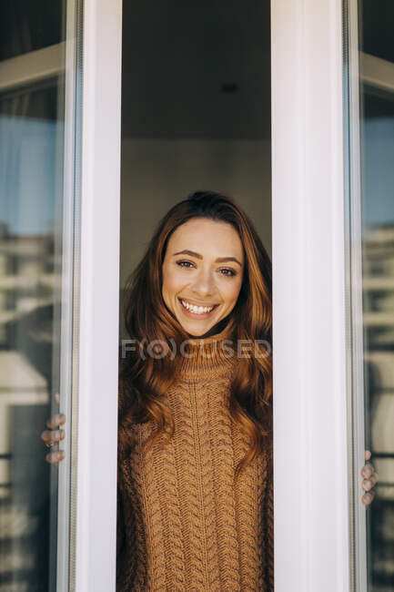 Portrait of happy young woman at the window — Stock Photo