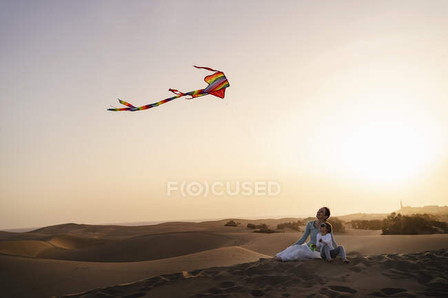 Mother and daughter flying kite in sand dunes at sunset, Gran Canaria, Spain — Stock Photo