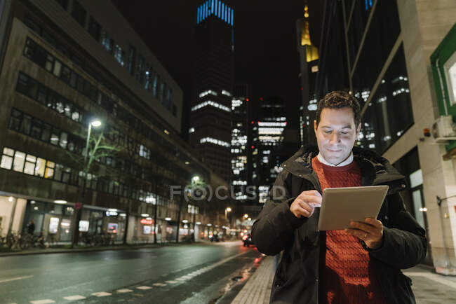 Ritratto di imprenditore sorridente in città con tablet digitale di notte, Francoforte sul Meno, Germania — Foto stock