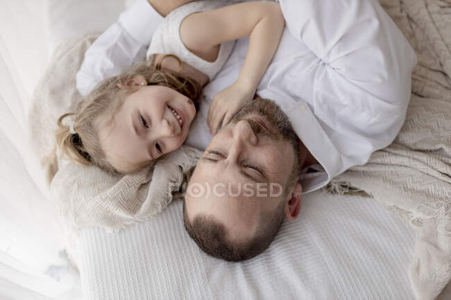 Отец и маленькая дочь отдыхают вместе на кровати. — стоковое фото