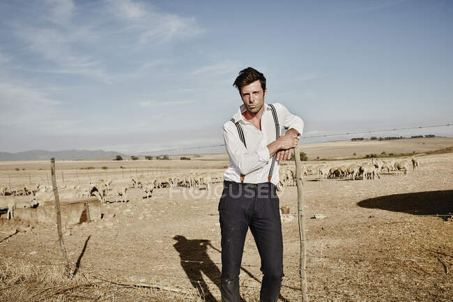 Retrato de homem em roupas antiquadas com rebanho de ovelhas em recinto — Fotografia de Stock