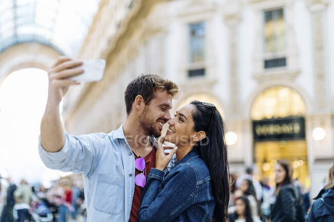 Feliz pareja joven tomando una selfie en la ciudad, Milán, Italia - foto de stock