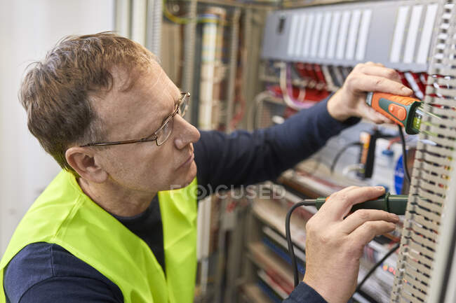 Electricista trabajando con voltímetro en caja de fusibles - foto de stock
