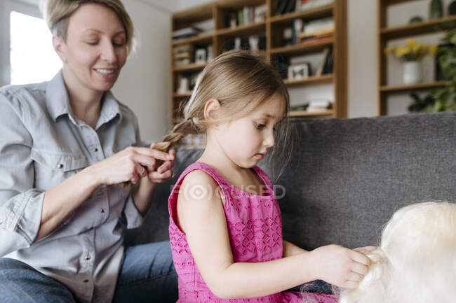 Мати вихваляє волосся дочки на дивані. — стокове фото