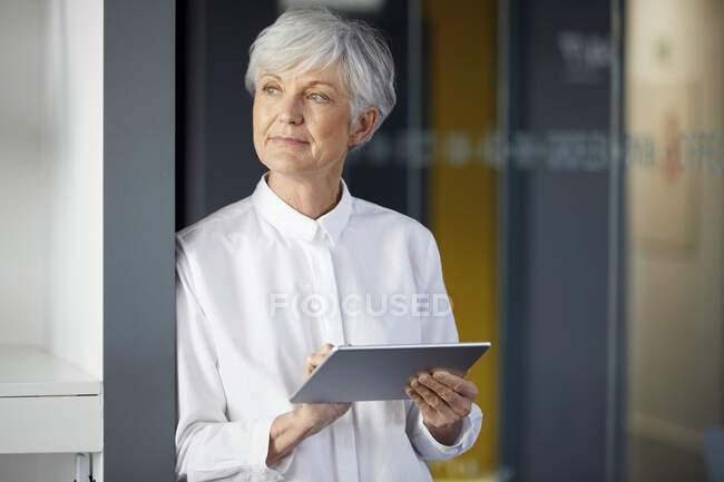 Retrato de mujer de negocios senior con tableta digital en la oficina - foto de stock