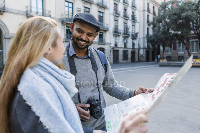 Pareja feliz con mapa de la ciudad mirándose, Barcelona, España - foto de stock