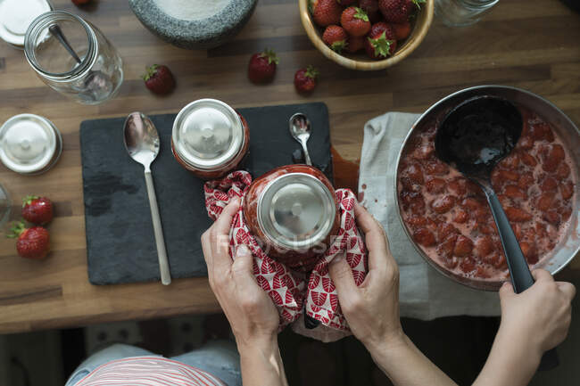 Vista sul raccolto di madre e figlia che preparano marmellata di fragole a casa — Foto stock