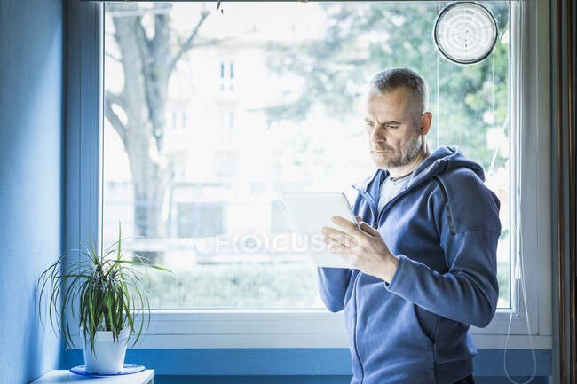 Mann benutzt digitales Tablet in der Nähe des Fensters — Stockfoto