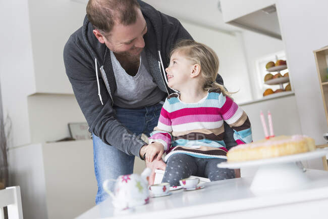 Father and daughter playing with doll's china set — Stock Photo