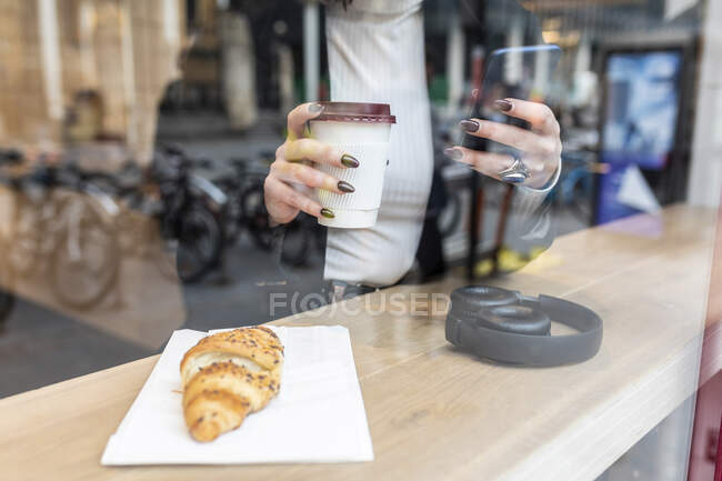 Gros plan d'une femme d'affaires prenant une pause café et utilisant son téléphone portable dans un café de la ville — Photo de stock