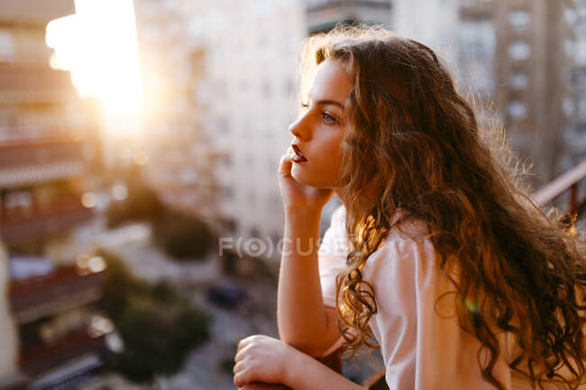 Portrait of beautiful young woman on balcony at sunset — Stock Photo