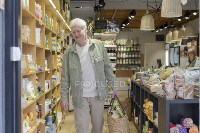 Smiling senior man buying groceries in a small food store — Stock Photo