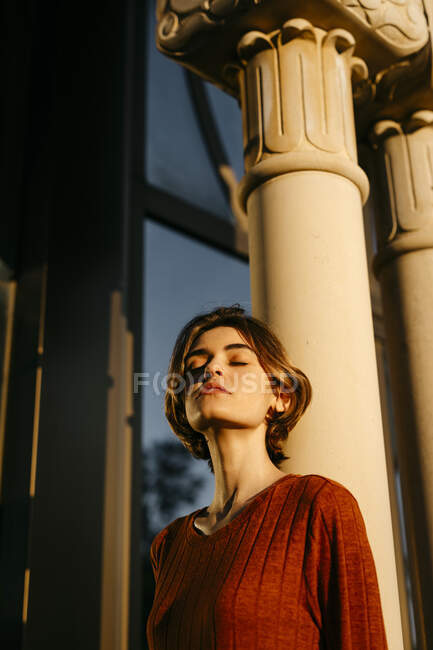 Retrato de mulher jovem com os olhos fechados apoiados em uma coluna — Fotografia de Stock