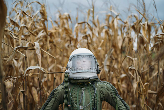 Young spaceman standing in wilted corn field — Stock Photo