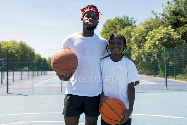 Отец и сын с мячами на баскетбольной площадке — стоковое фото