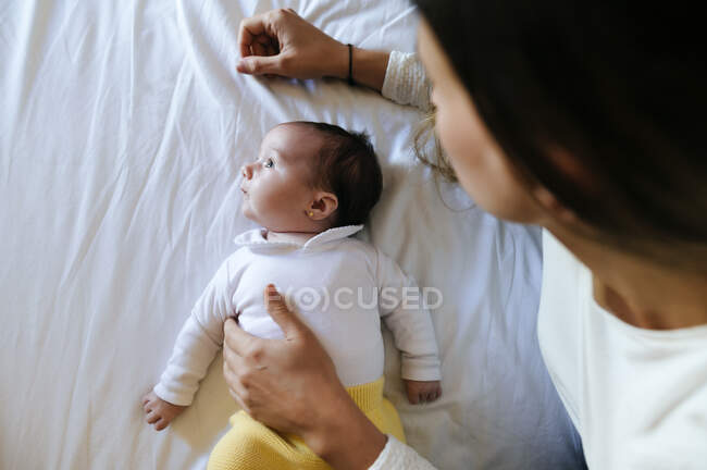 Bambina sdraiata a letto mentre la madre la tocca — Foto stock