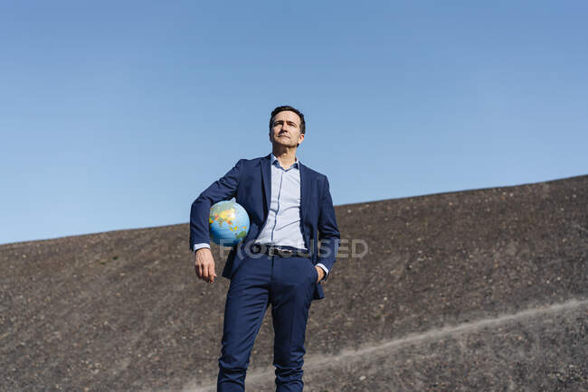 Maduro hombre de negocios sosteniendo un globo en una punta de mina en desuso - foto de stock