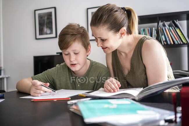 Mother homeschooling her son at home — Stock Photo