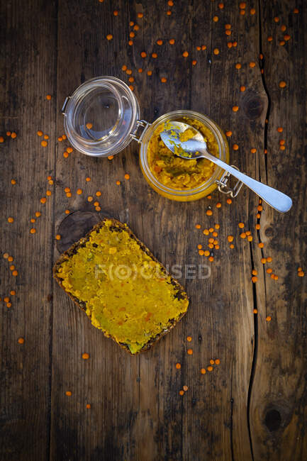Jar of homemade red lentil paste and slice of wholegrain bread — Stock Photo