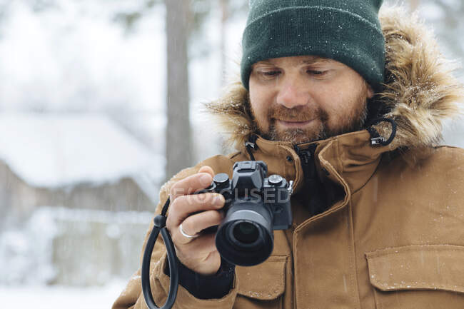 Портрет улыбающегося мужчины, смотрящего на цифровую камеру зимой — стоковое фото