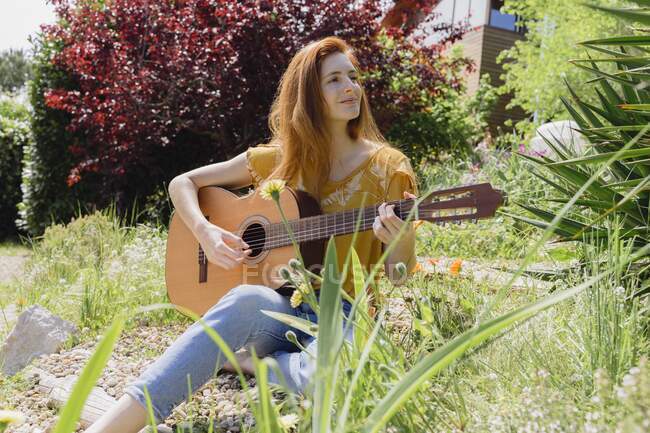 Sorridente giovane donna che suona la chitarra in natura — Foto stock