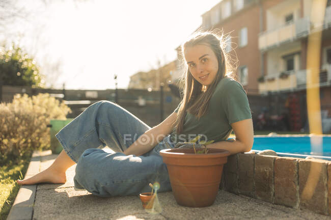 Молода жінка в саду з розсадою в вазоні — стокове фото