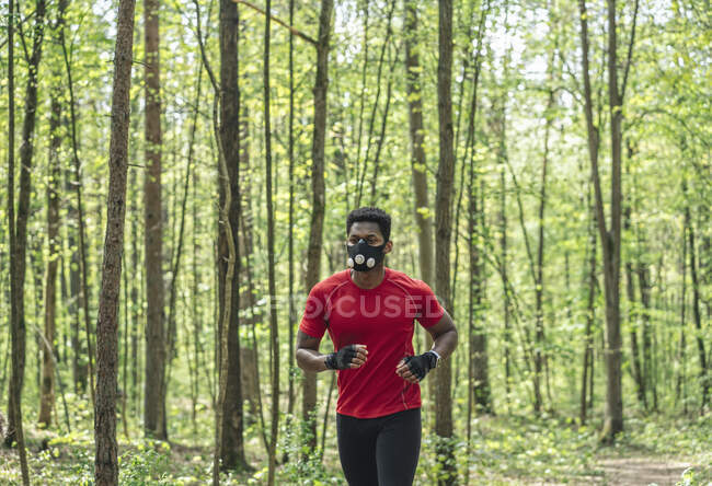 Спортсмен у масці для обличчя біжить в лісі. — стокове фото