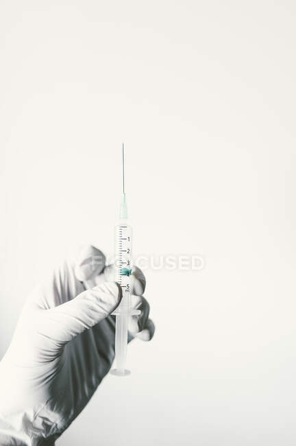 Main avec gant protecteur, tenant le sirop avec le vaccin — Photo de stock