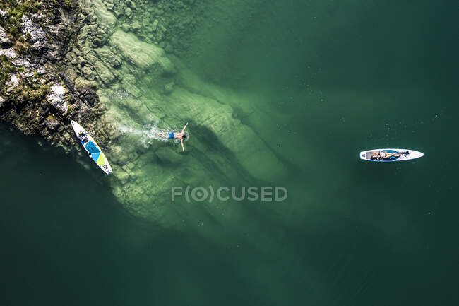 Germany, Bavaria, Aerial view of two paddleboarders relaxing on green shore of Lake Walchen — Stock Photo