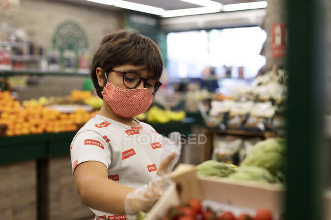 Мальчик принимает овощи в супермаркете — стоковое фото