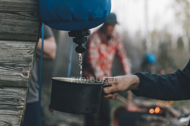 Pessoa que enche a frigideira com água em um acampamento ao ar livre — Fotografia de Stock