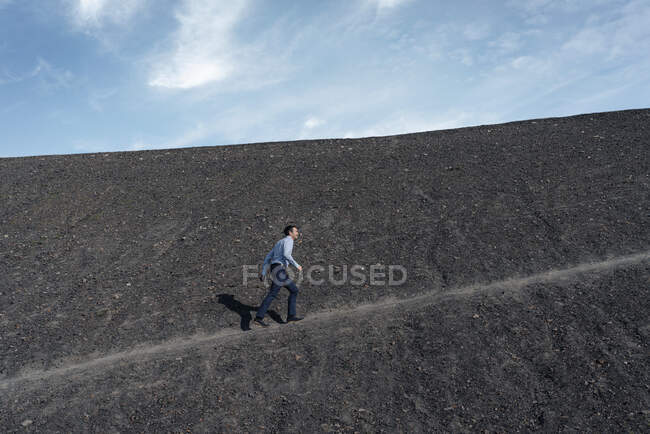 Reifer Geschäftsmann geht eine stillgelegte Minenspitze hinauf — Stockfoto