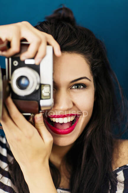 Portrait of young woman with red lips taking picture of viewer with camera — Stock Photo