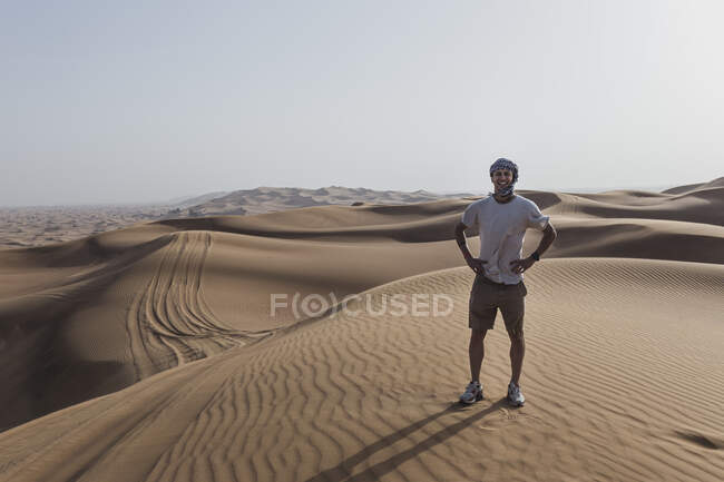 Buon turista maschio in piedi sulle dune di sabbia nel deserto a Dubai, Emirati Arabi Uniti — Foto stock