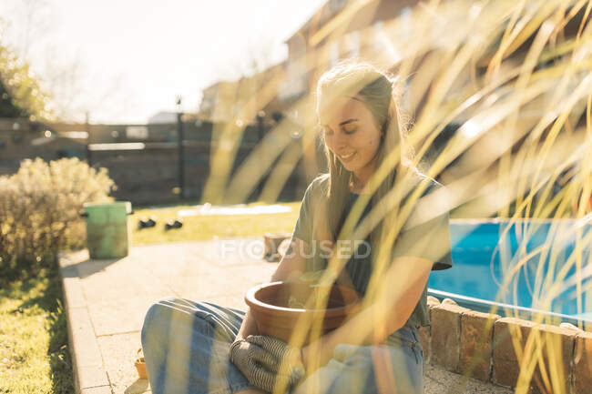 Jovem mulher no jardim com plântulas em vaso — Fotografia de Stock