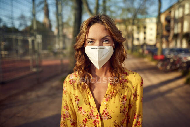 Rothaarige Frau mit FFP2-Gesichtsmaske in der Stadt — Stockfoto