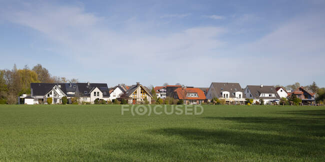 Germany, North Rhine-Westphalia, Kamen, Panorama of green meadow in front of rural houses — Stock Photo