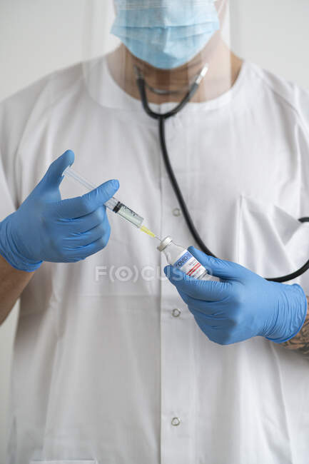 Mann in Schutzkleidung bereitet Covid-19-Impfung vor — Stockfoto
