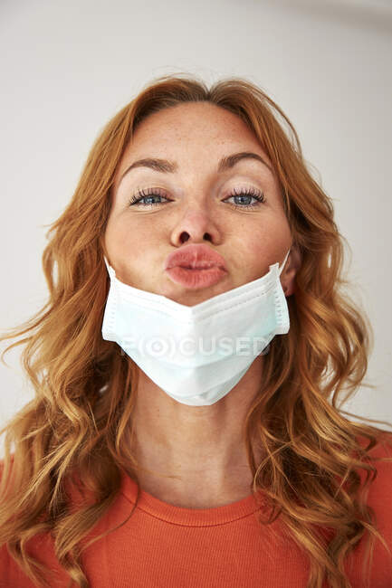 Porträt einer rothaarigen Frau mit küssenden Lippen über einer Schutzmaske — Stockfoto
