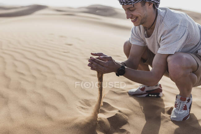 Buon turista maschio che gioca con la sabbia nel deserto a Dubai, Emirati Arabi Uniti — Foto stock