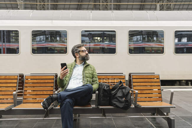 Mann sitzt auf einer Bank am Bahnhof — Stockfoto