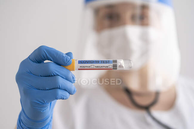 Woman in protective wear holding covid-19 test — Stock Photo