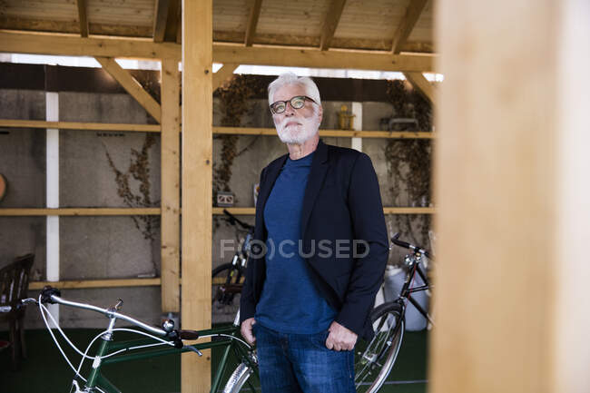 Retrato del hombre mayor sentado con bicicleta de carreras de pie en un refugio - foto de stock