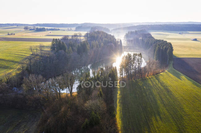 Germany, Bavaria, Egling, Drone view of rising sun reflecting in Thanninger Weiher lake — Stock Photo