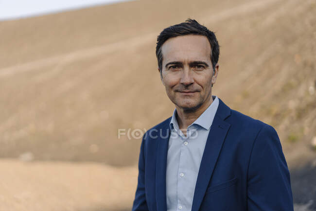Porträt eines selbstbewussten reifen Geschäftsmannes auf einer stillgelegten Minenspitze — Stockfoto
